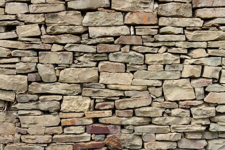 Fragment of a wall from a natural mountain stone with a small impregnation of dry branches in the summer day. North Caucasus. Highlanders Architectureの写真素材