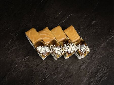 Mini-set of two types of rolls in the Japanese style on a dark background, top view, close-up. Salmon rolls without sauce. Rolls poured with dark sauce and sprinkled with sesame seeds. Southeast Asia Cuisineの写真素材
