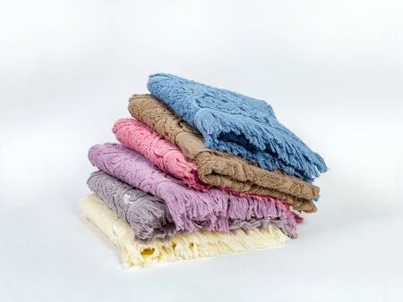 A stack of towels of different colors are stacked on a light background. Stack falls to one sideの写真素材