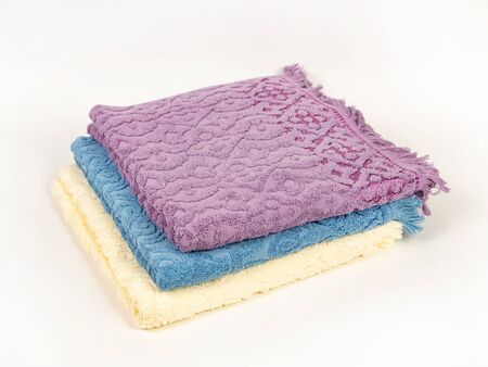 Three towels of different colors with a fringe are stacked in a stack on a light background. Lavender, Blue, Light Yellowの写真素材