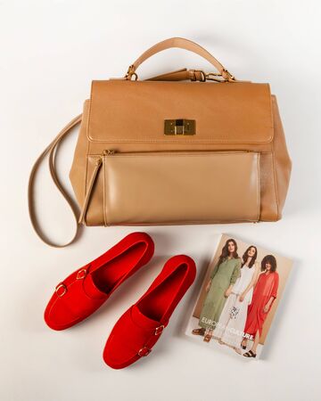 Women bag, light brown, red women shoes and a magazine about style and fashion, top view. Gold buckles and locks, close-up, on a light backgroundのeditorial素材