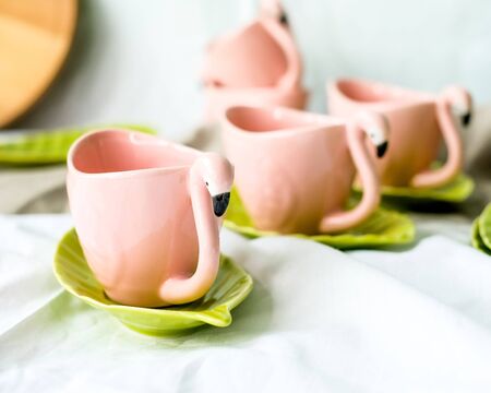 Set of decorative mugs and saucers on a white background. Fantasy birds. Pink flamingo. Tea party. Selective focusの写真素材