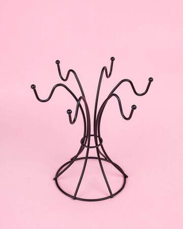 Rack-hanger for mugs of black on a pink background. Compact storage of dishes. Vertical layoutの写真素材