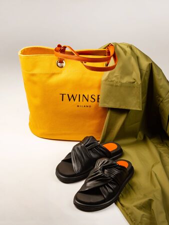 Yellow women bag, green dress and black slippers on a light background. Vertical layoutのeditorial素材