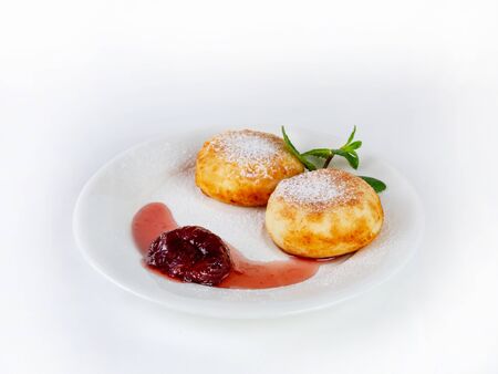 Cheesecakes with strawberry jam on a plate, decorated with mint leaves, side view. Sprinkled with powdered sugar. On white backgroundの写真素材