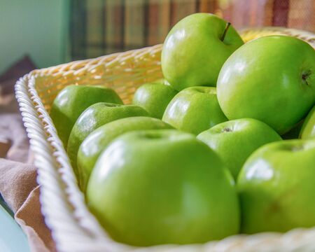 Plastic basket with green apples in the morning light. Close up, selective focus, side viewの写真素材