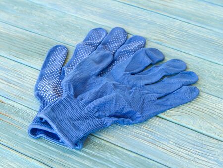 Blue construction gloves on a wooden plank background close-up. Rubber spraying, craft, hand...