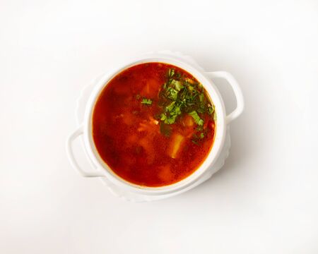 Vegetable soup in a plate on a white plate with chopped herbs, top view. Serving the first course in...