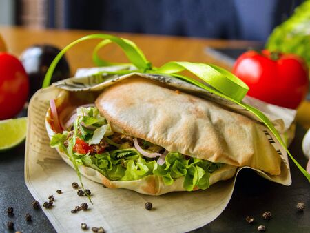 Vegan appetizer, thin dough cake stuffed with fresh chopped vegetables on a serving plate. The dish is packaged for delivery. Peas of black pepper. Tomatoes, lettuce, onionsの写真素材