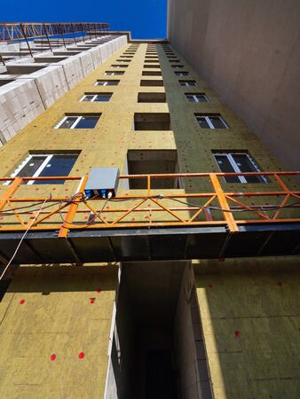 A fragment of a building covered with special heat-insulating material. View from below. Builder freight elevatorのeditorial素材