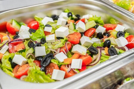 Greek salad in stainless bowl close-up. Bistro menu, chopped vegetables and cheese. Appetizing mix. Selective focusの写真素材