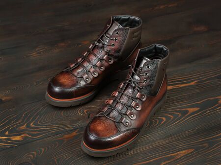 A pair of brown leather army-style boots on a wooden floor. Lacing, fittings. Selective focusの写真素材