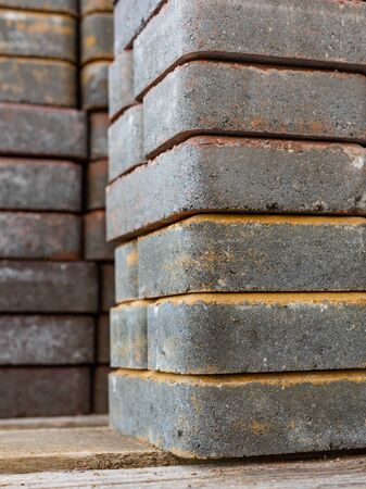 The paving slabs are stacked in a pile on a wooden pallet. Vertical layout. Improvement of streets and courtyards. Building technology. Grain. Close up, selective focusの写真素材