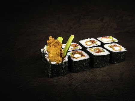 Rolls with a delicious filling of batter-fried fish, slices of avocado, sweet pepper, tobiko caviar and sauce. Side view, close up. Selective focusの写真素材