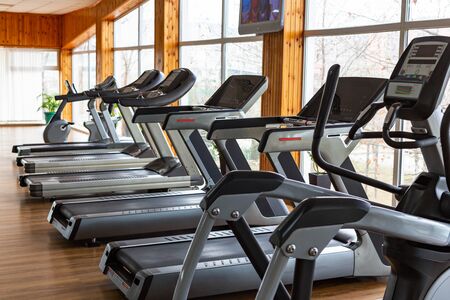 Exercise machines for running stand in a row in the gym with panoramic windows. Daylight, selective focusの写真素材