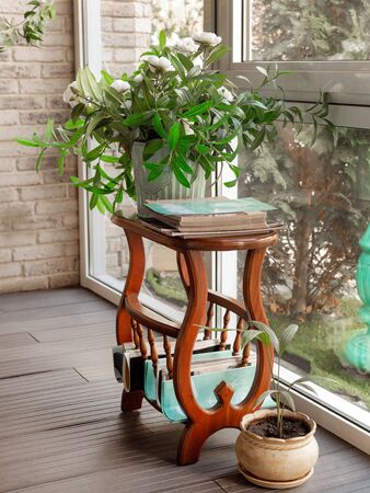 On a table with magazines is a large pot of homemade flowers. Daylight, vertical layout. Selective focusの写真素材