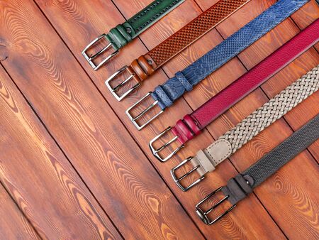 A set of different trouser belts on a plank background. Close up, top view. Abandoned varnished woodの写真素材