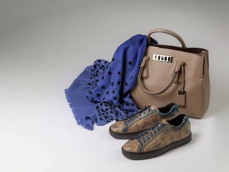 Leather sneakers, leather bag, blue woolen scarf with ornament in the form of stars on a light background. Copyspace on the leftの写真素材