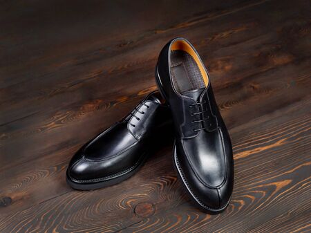 An assortment of boutique men's classic shoes. Black shoes with an orange lining. One on top of another, close up. Side viewの写真素材