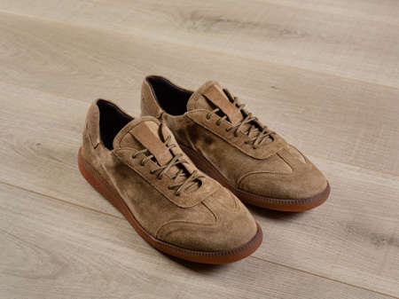 Soft light brown men's shoes for sports lying on a surface of light boards, close-up, selective focusの写真素材