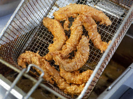 The boiling oil frying of the nuggets is complete. Large chunks of deep-fried chicken are ready to...
