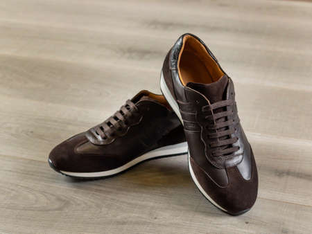 Sneakers made of leather of various finishes lie on a surface of light boards, close-up, selective focusの写真素材