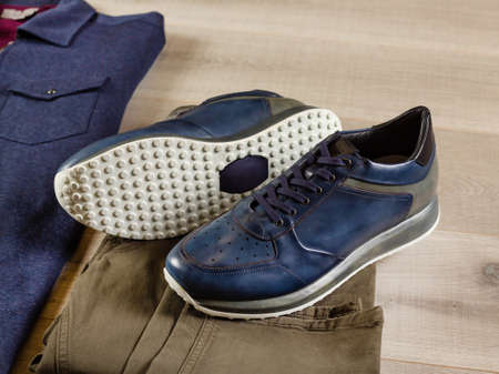 Men's sneakers lie on jeans of a swamp shade, close-up, side viewの写真素材
