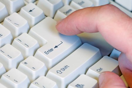 Male finger hitting the enter key on a keyboard.