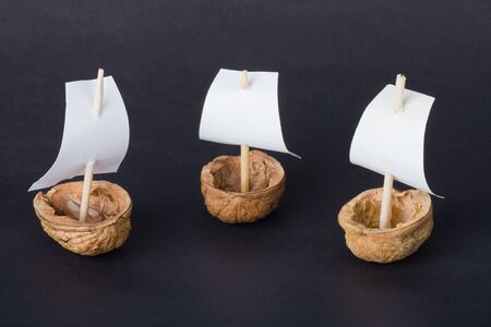 Three little boats made from walnut shell on black background.の写真素材