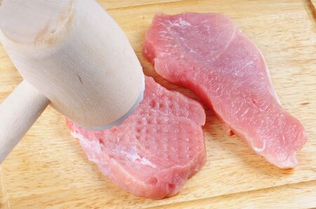 Tenderization of fresh pork steak on wooden chopping board.の写真素材
