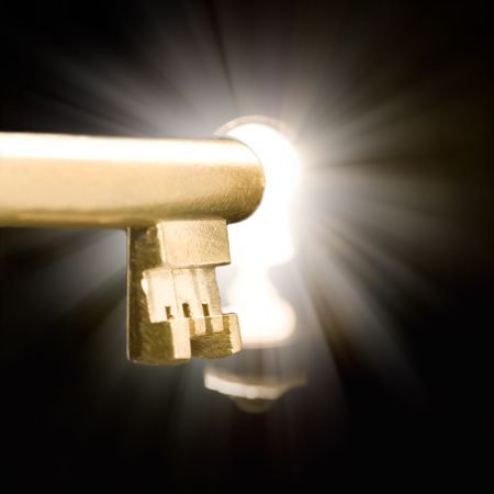 A golden key in a keyhole illuminated by a mysterious lightの写真素材
