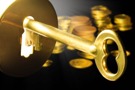 Golden key to the fortune with columns of coinsの写真素材