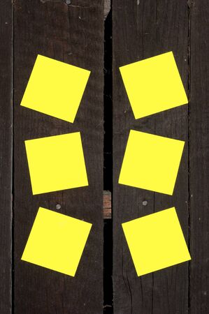 Yellow sticky notes on a wooden wall.の写真素材