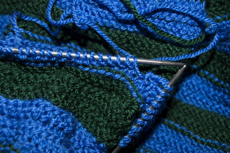 the process of knitting the scarf in two colors - blue and green