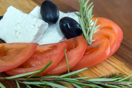 Fresh salad with tomatoes, feta cheese and olives on wooden backgroundの写真素材