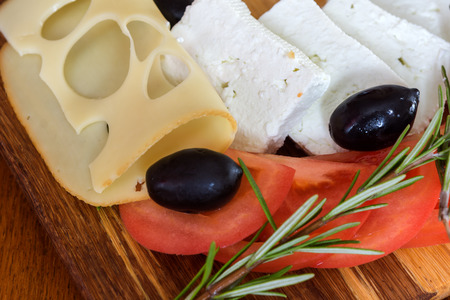 Fresh salad with tomatoes, feta cheese and olives on wooden backgroundの写真素材