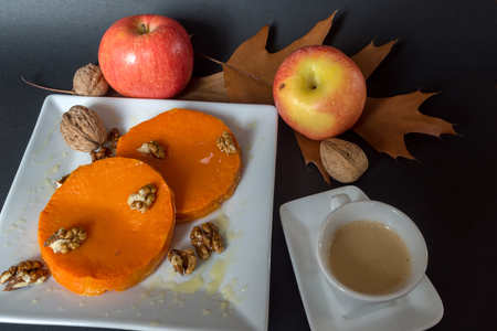 Roasted, baked pumpkin with addition of Honey and walnuts, autumn leafs and  cup of coffeeの写真素材