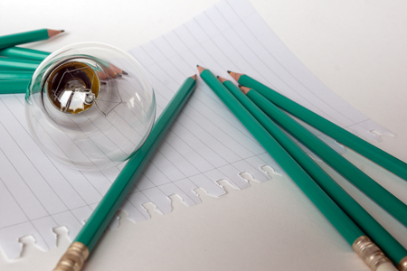 Composition with Light bulb with notebook and pencils on white backgroundの写真素材
