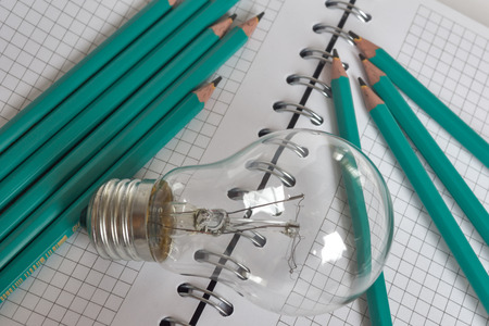 Composition with Light bulb with notebook and pencils on white backgroundの写真素材