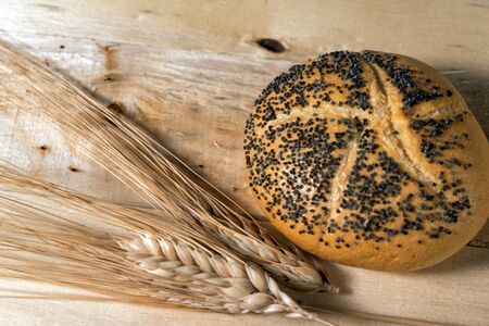 Small bread with poppy seeds and Wheat on wooden backgroundの写真素材