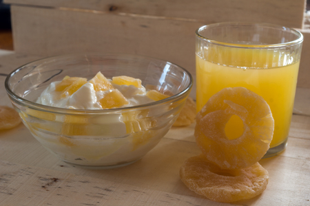 Breakfast with Yogurt with pieces of pineapple and orange juice on a wooden backgroundのeditorial素材