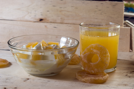 Breakfast with Yogurt with pieces of pineapple and orange juice on a wooden backgroundのeditorial素材