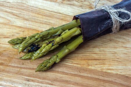 Organic grilled and marinated asparagus prepare for cooking on wooden backgroundの写真素材