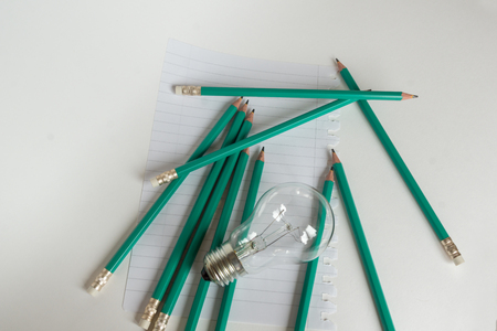Business Composition with Light bulb with notebook and pencils on white backgroundの写真素材