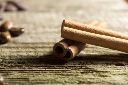Cinnamon sticks with coffee grains on wooden background