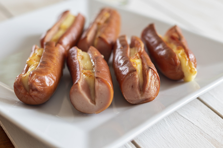 Roasted sausage with yellow cheese over white wooden backgroundの写真素材