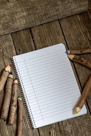 Pencils made of branches and a notebook on a wooden backgroundの写真素材