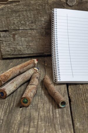 Pencils made of branches and a notebook on a wooden backgroundの写真素材