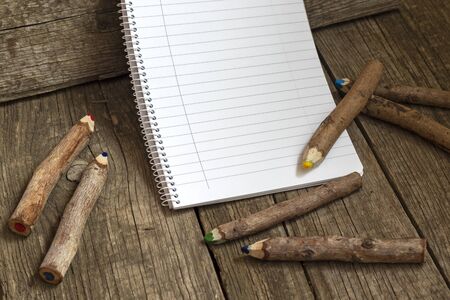 Pencils made of branches and a notebook on a wooden backgroundの写真素材