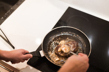 the process of cooking beef steak in a frying pan with butter and rosemaryの写真素材